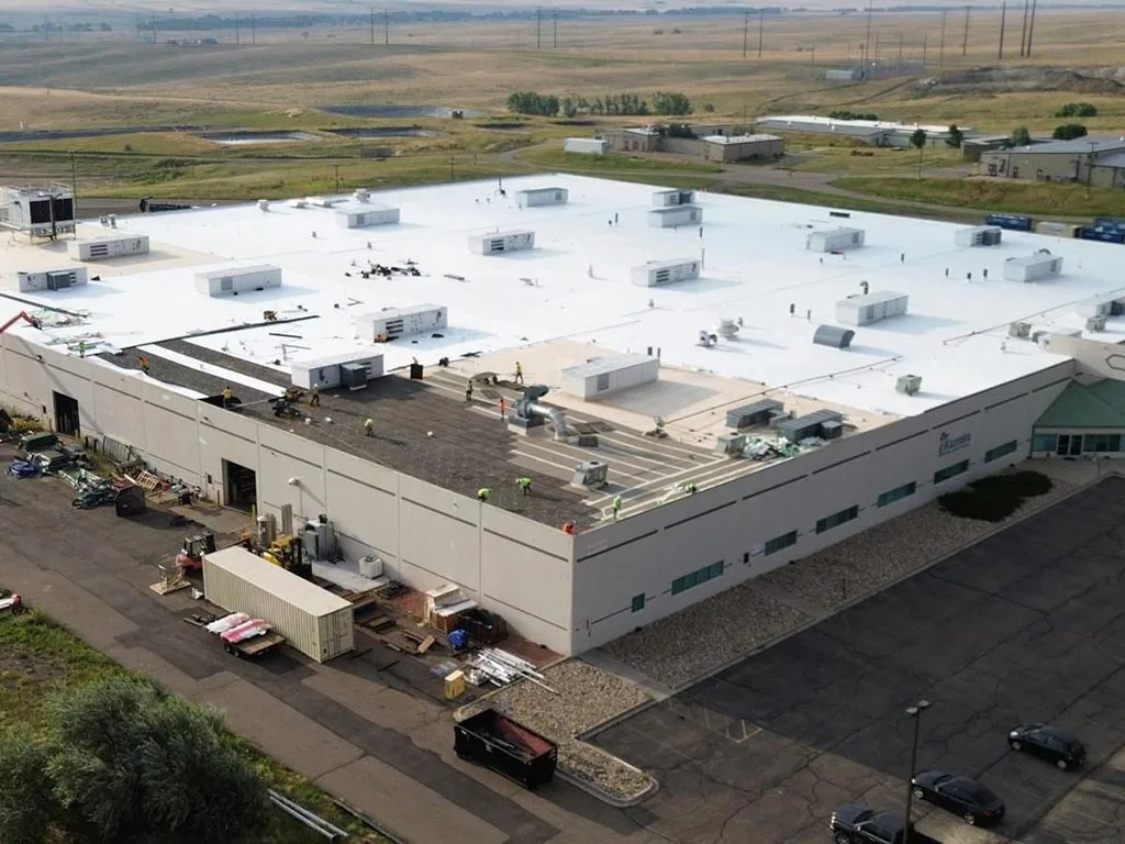 Evolve Construction team working on a large commercial roof project with multiple structures